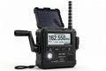 Rugged black NOAA weather radio with open solar panel, antenna, hand crank and digital display on white background